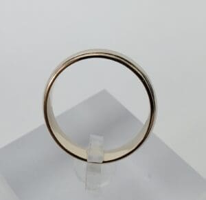 Gold ring displayed on clear stand.