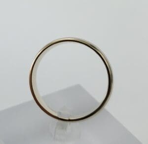 Gold wedding band displayed on stand.
