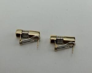 Two gold and silver clip-on earrings.