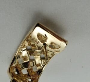 Gold belt buckle with intricate design.