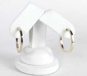 Gold hoop earrings on white display stand.