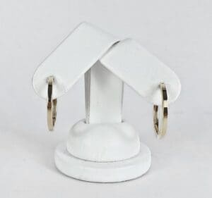 Gold hoop earrings on white display stand.
