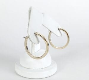 Gold hoop earrings on white display stand.
