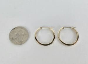Gold hoop earrings beside a quarter.