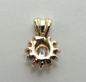 Gold pendant with a central clear gemstone.