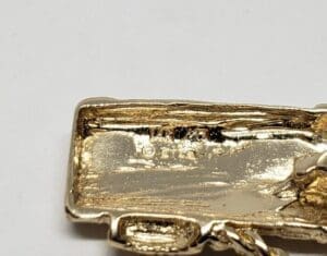 Gold-colored metal object with engraved text.