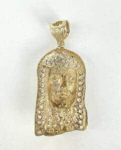 Gold pendant with face and embedded stones.