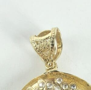 Gold pendant with intricate design and stones.
