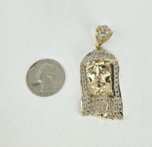 Gold pendant next to a quarter coin.