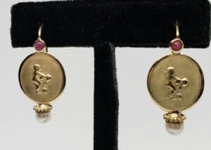Gold earrings with embossed figures and pearls.
