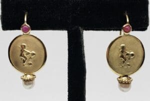 Gold earrings with embossed figure design.