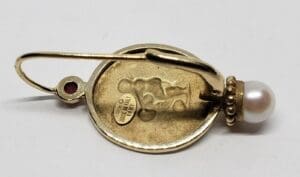 Gold earring with pearl and red stone.