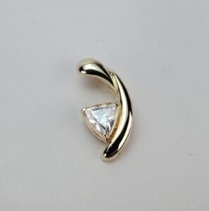 Gold pendant with triangular clear gemstone.