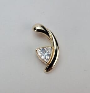 Gold pendant with triangular gemstone design.