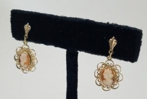 Vintage cameo earrings on black display stand.