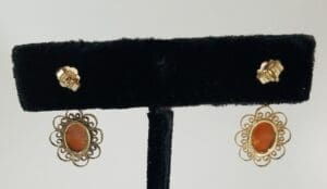 Gold earrings with orange stones displayed.