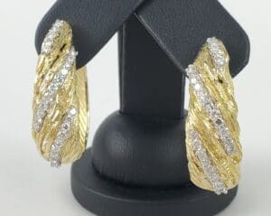 Gold and diamond earrings on display stand.