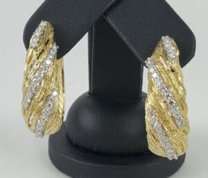 Gold and diamond earrings on display stand.