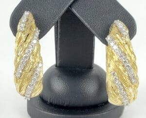 Gold and diamond textured earrings display.