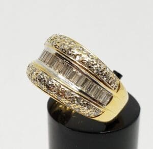 Gold ring with diamonds on black stand.