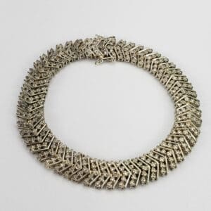 Diamond-patterned silver necklace on white background.