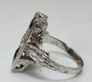 Ornate silver ring with green stones.