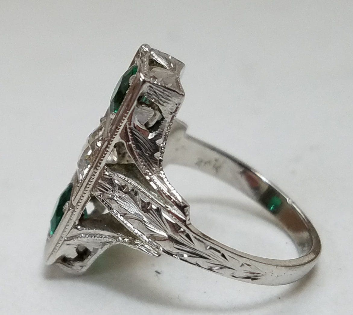Ornate silver ring with green stones.