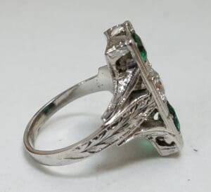 Silver ring with green gemstones, side view.