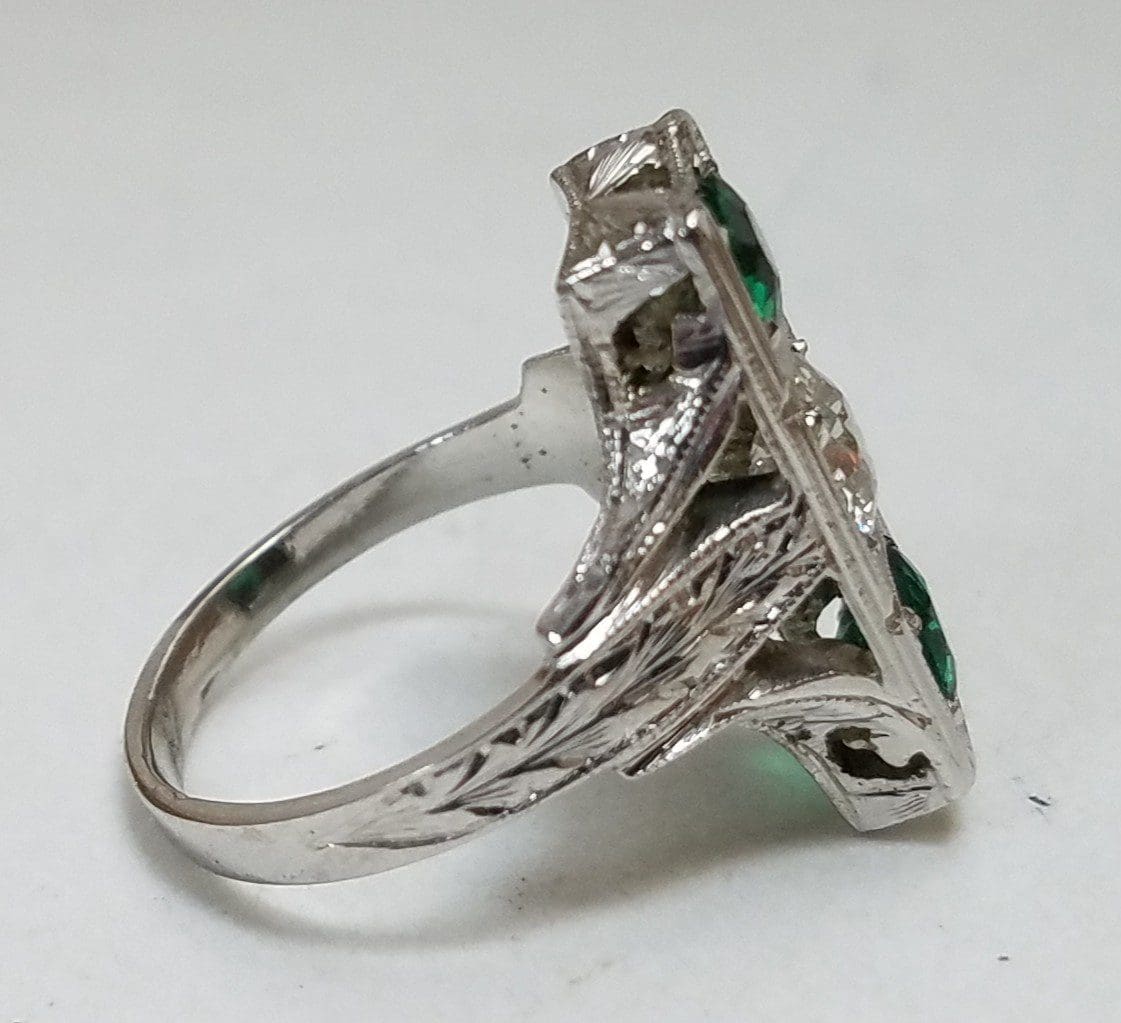 Silver ring with green gemstones, side view.