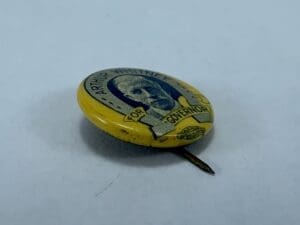 Yellow campaign button with a portrait graphic.