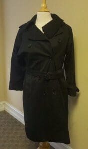 Black trench coat on a mannequin stand.