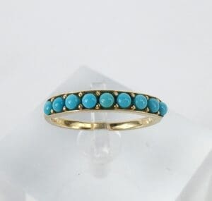 Gold ring with turquoise stones on display.