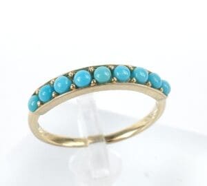 Gold ring with turquoise stones on display.