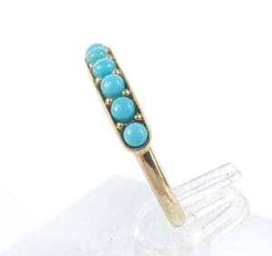 Gold ring with turquoise gemstones displayed.