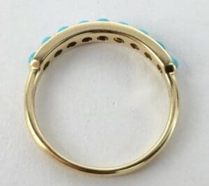 Gold ring with turquoise stones on top.