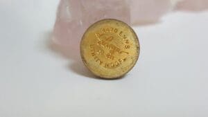 Gold button with engraved text on display.