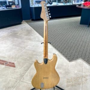 Wooden electric guitar on display stand.