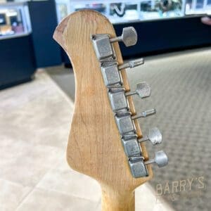 Guitar headstock with tuning pegs, indoors.
