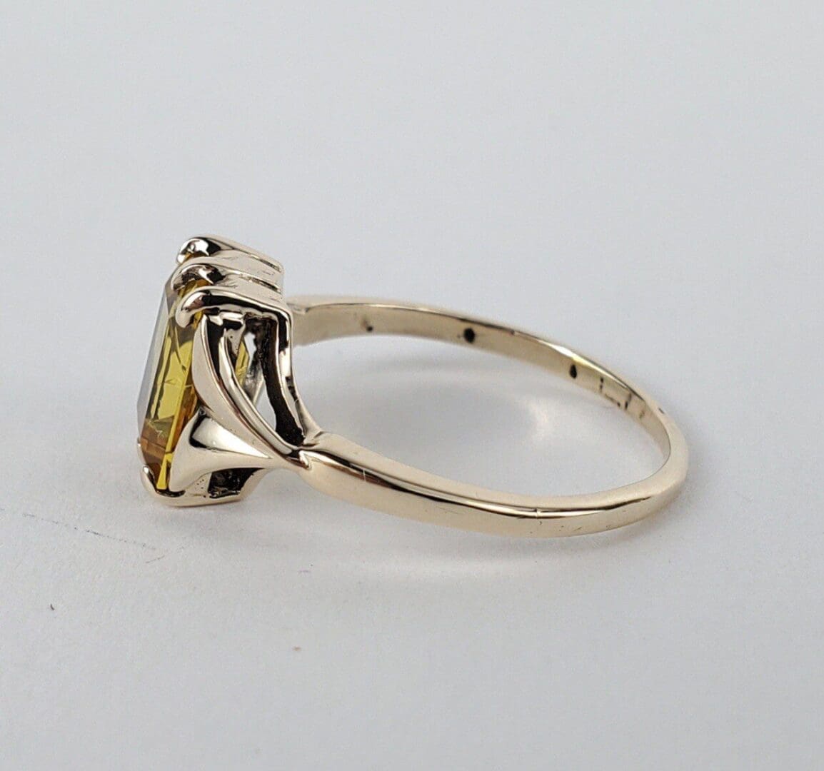 Gold ring with yellow gemstone side view.