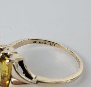 Gold ring with yellow gemstone and inscription.