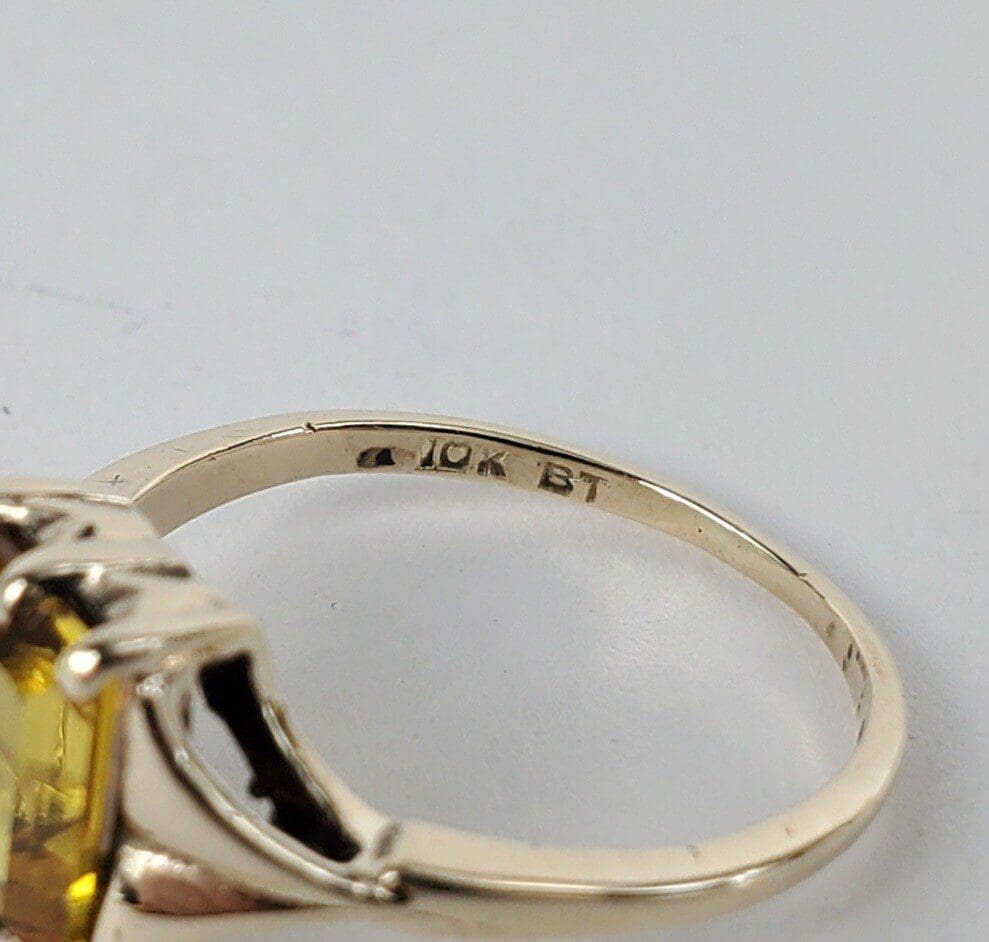 Gold ring with yellow gemstone and inscription.
