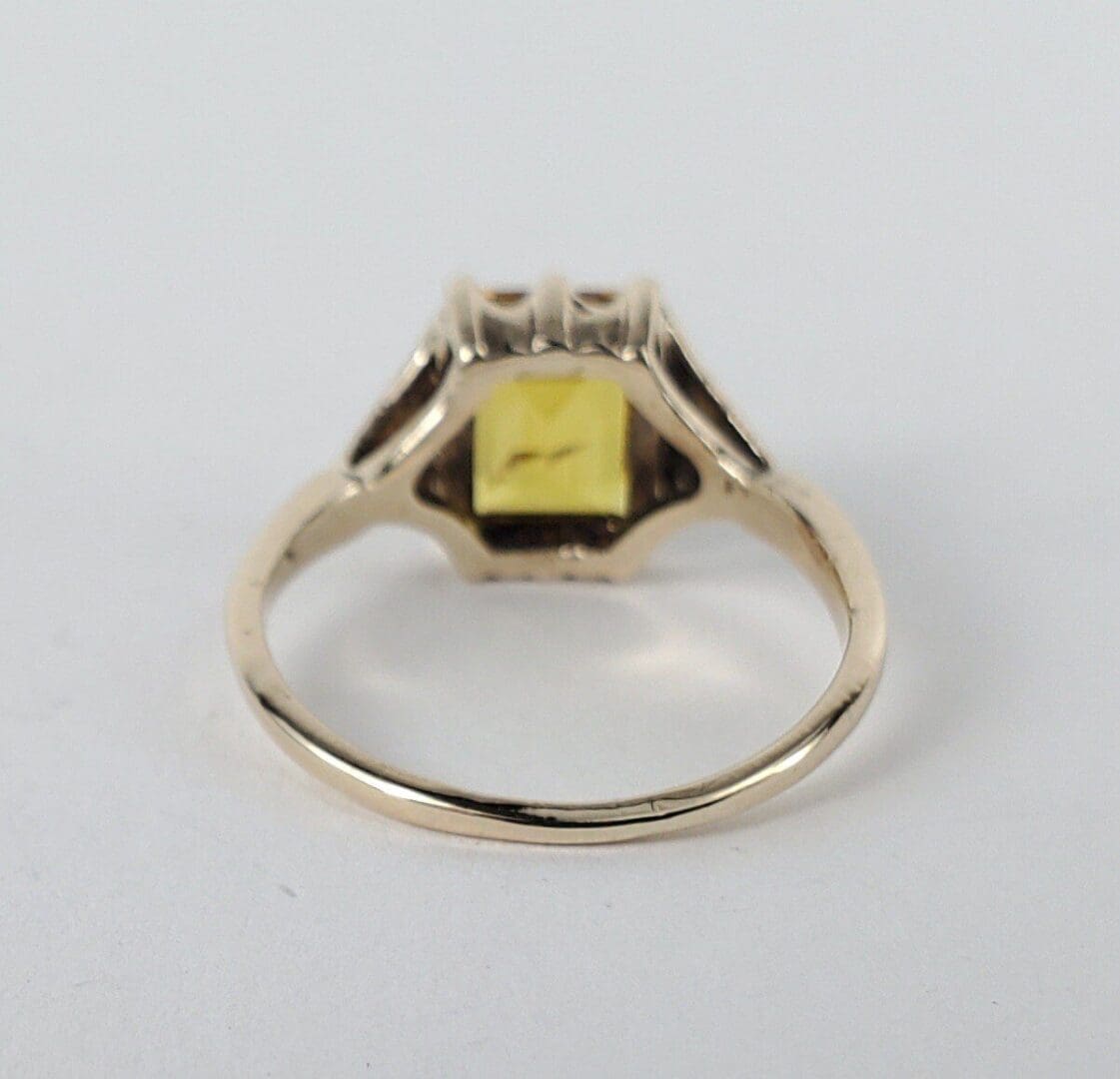 Gold ring with square yellow gemstone.
