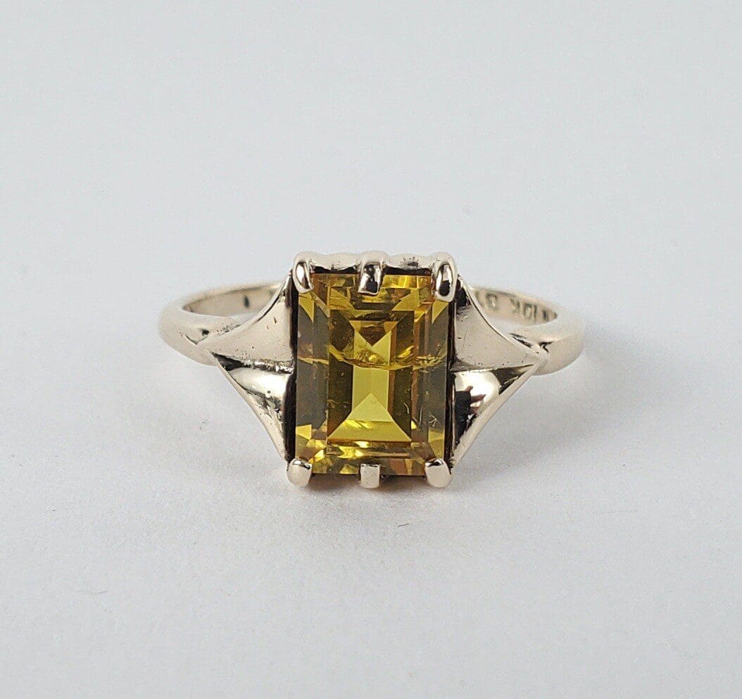 Gold ring with yellow rectangular gemstone.