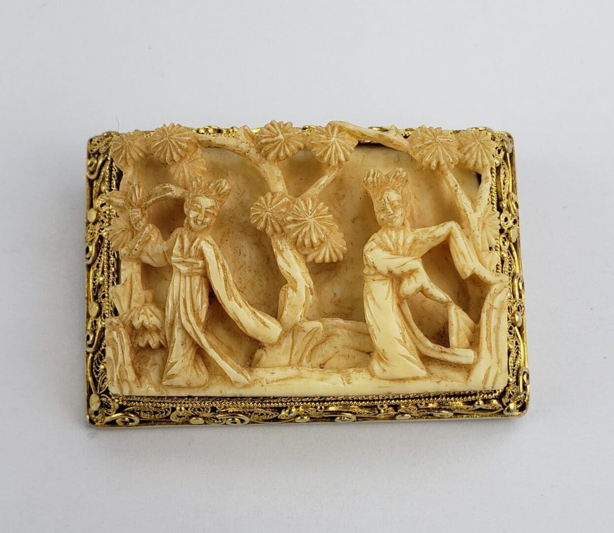 Intricate carved scene with figures and trees.