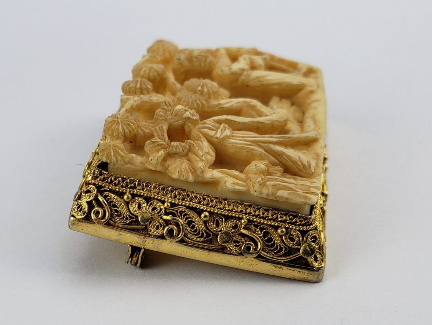Ornate carved brooch with floral design.