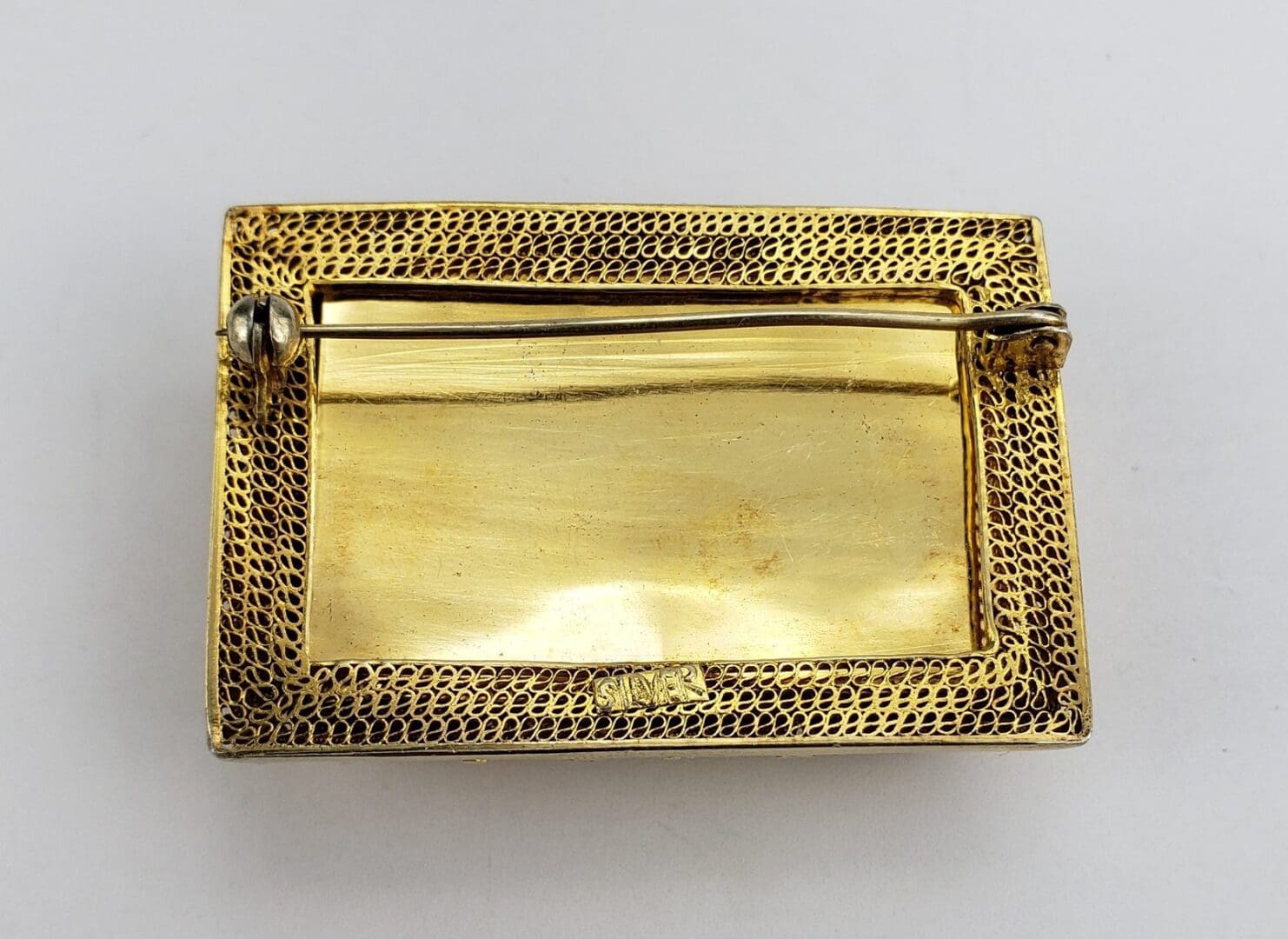 Back view of a gold rectangular brooch.