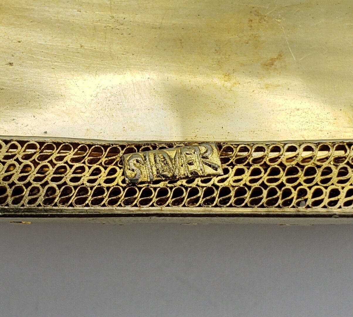 Silver mesh texture with engraved label.