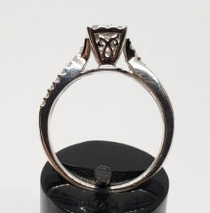 Silver engagement ring on black stand.
