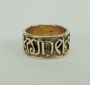 Gold ring with engraved decorative script.