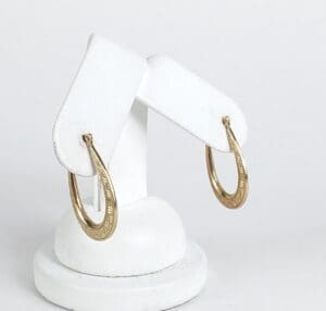 Gold hoop earrings on white stand.